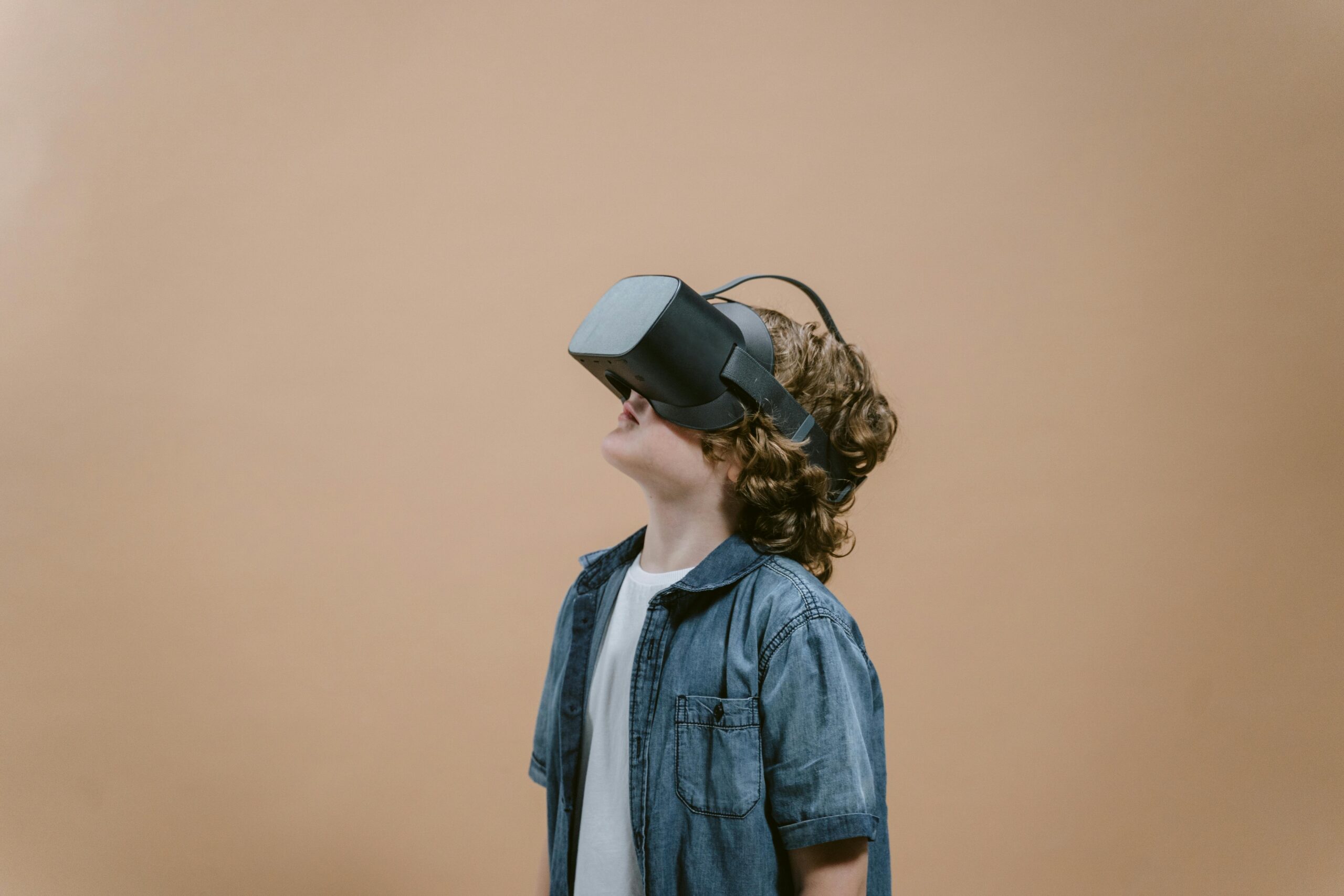 A young boy exploring virtual reality with a VR headset in a studio setting.